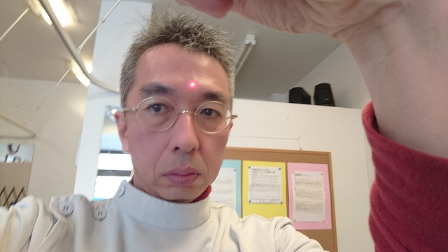 院長が自分自身で非接触型体温計を用いて検温している時の写真